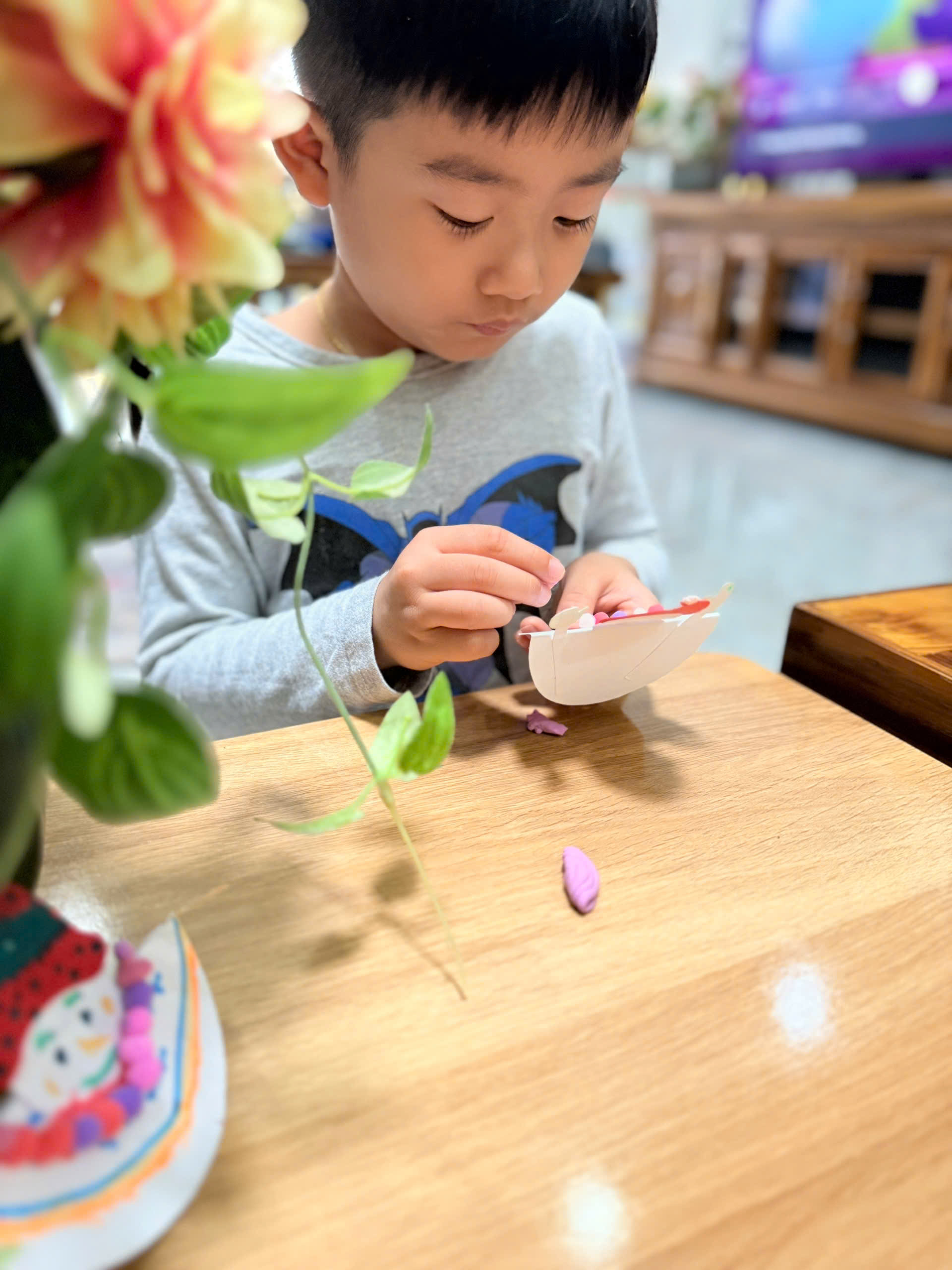 Babysitter guiding a child to make a paper snowman craft (screen-free) during daily care