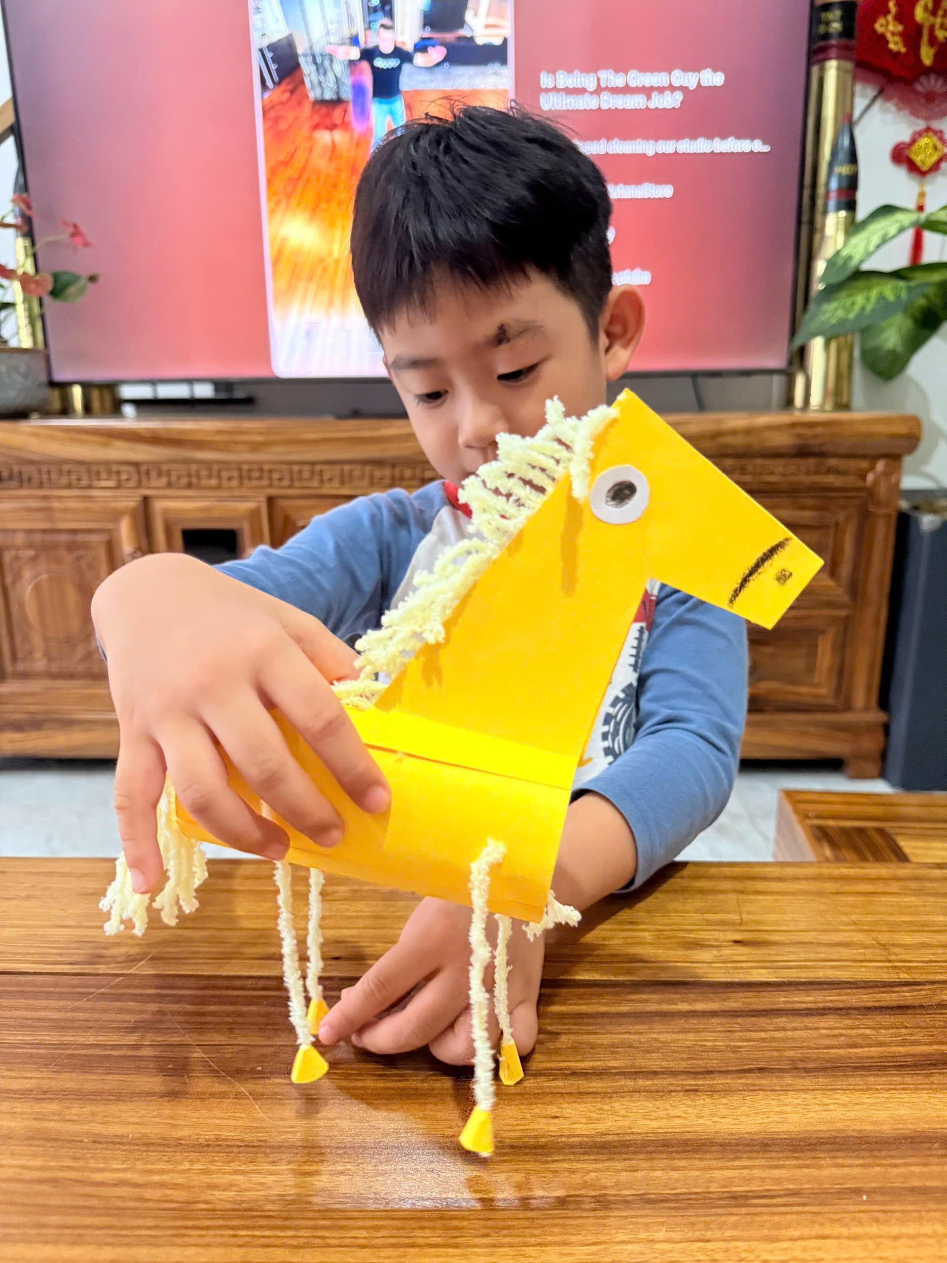 Babysitter guiding a child to make a paper horse craft